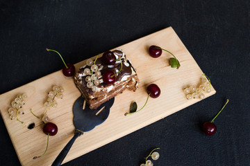 Top view of a slide of chocolate cake with a cherry on a black background