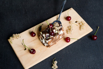 Top view of a slide of chocolate cake with a cherry on a black background