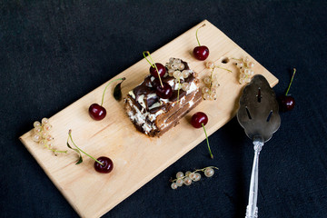Top view of a slide of chocolate cake with a cherry on a black background