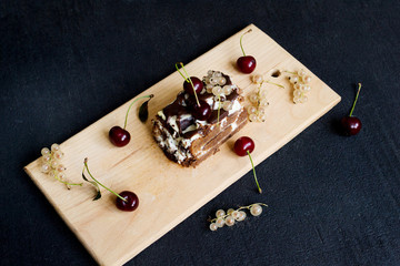 Top view of a slide of chocolate cake with a cherry on a black background