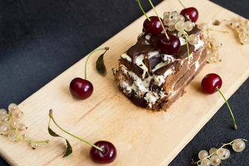 Top view of a slide of chocolate cake with a cherry on a black background