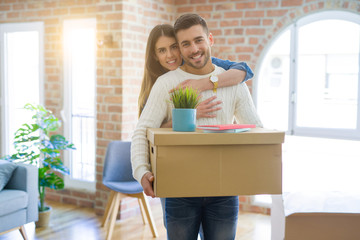 Beautiful young couple moving to a new house, smiling happy holding cardboard boxes at new apartment