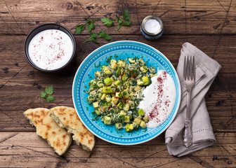 Traditional Turkish fried eggs with zucchini and herbs with yoghurt garlic sauce and fresh tortillas on a wooden table, top view. delicious healthy breakfast