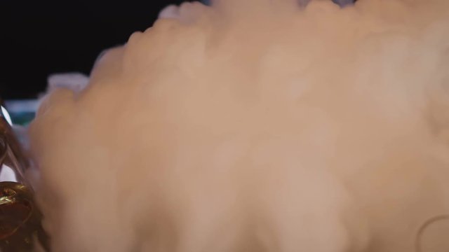White cold smoke spreads out from a bucket of dry ice. Bar counter with glasses of alcohol in a bucket of dry ice. Cooking chilled alcoholic cocktails.