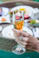 Close up image of a woman holding a glass of champagne, a meal next to the pool, leisure vacation travel summertime concept