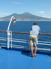 Homme sur le pont d'un bateau en arrivant à Naples  avec vue sur le volcan Vésuve