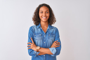 Young brazilian woman wearing denim shirt standing over isolated white background happy face smiling with crossed arms looking at the camera. Positive person. - obrazy, fototapety, plakaty