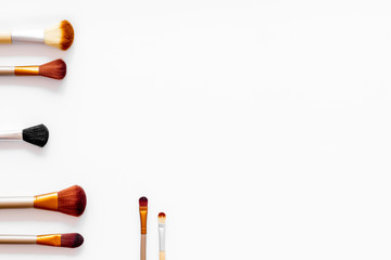 Brushes for make up on white visagiste work desk background top view copyspace