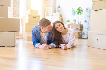 Obraz na płótnie Canvas Young beautiful couple relaxing lying on the floor around cardboard boxes at home, smiling happy moving to a new house