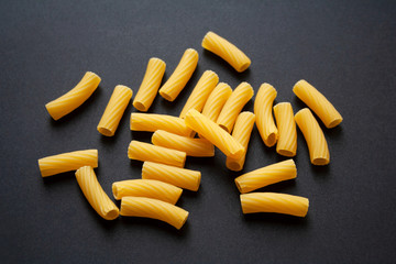 Heap of raw tortiglioni pasta isolated on black background