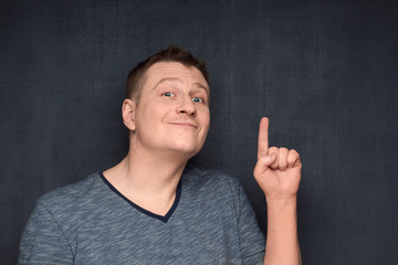 Portrait of contented man pointing up with finger