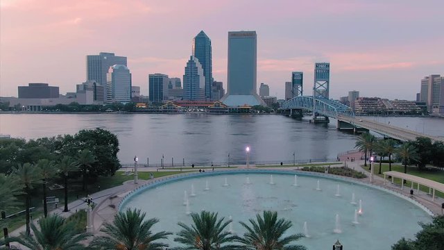 Aerial: Establishing shot of Jacksonville, st Johns river, large fountain & John T Alsop Jr bridge at sunset. Florida, USA. 2 July 2019