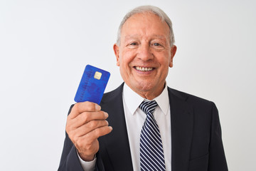 Senior grey-haired businessman holding credit card over isolated white background with a happy face standing and smiling with a confident smile showing teeth