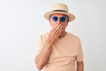 Senior man wearing striped t-shirt sunglasses and sumer hat over isolated white background cover mouth with hand shocked with shame for mistake, expression of fear, scared in silence, secret concept