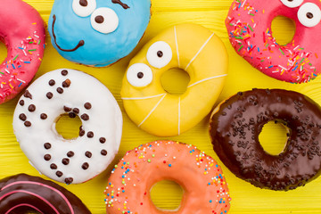 Different donuts background. Close up assorted donuts on yellow background. Yummy frosted treats.