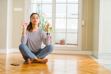 Young beautiful woman sitting on the floor at home relax and smiling with eyes closed doing meditation gesture with fingers. Yoga concept.