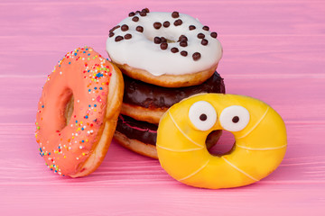 Colored donuts on pink wooden background. Tasty creamy glazed donuts on wooden background.