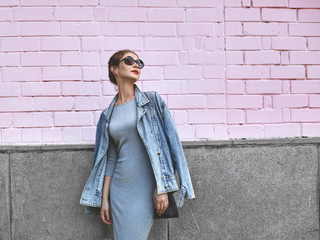 Street Style Shoot Woman on Pink Wall. Swag Girl Wearing Jeans Jacket, grey Dress, Sunglass....