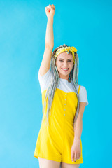 girl with dreadlocks cheering with clenched fist isolated on turquoise