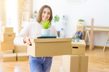 Fototapeta na wymiar Beautiful young woman smiling happy moving to a new home, very excited holding cardboard boxes at new apartment