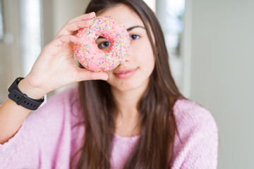 Beautiful young woman eating pink chocolate chips donut with a confident expression on smart face thinking serious