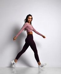 Young athletic woman brunette girl in a good shape in trendy sportswear walking in gym uniform does cardio exercises 