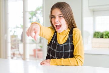 Young beautiful blonde kid girl wearing casual yellow sweater at home pointing displeased and...