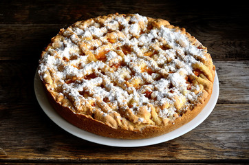 Homemade apricot pie in a white plate on a wooden table.