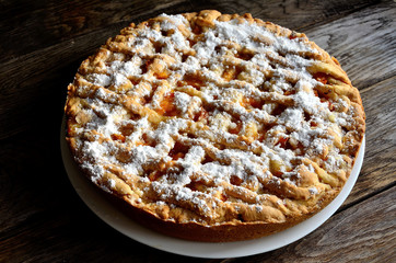 Homemade apricot pie in a white plate on a wooden table.