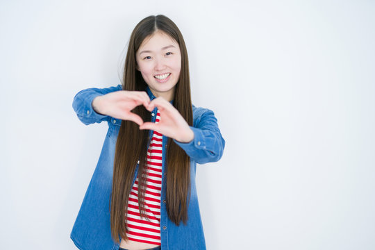Beautiful young asian woman over white isolated background smiling in love showing heart symbol and shape with hands. Romantic concept.