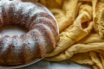 Pumpkin cake on a white dish on yellow fabric. 