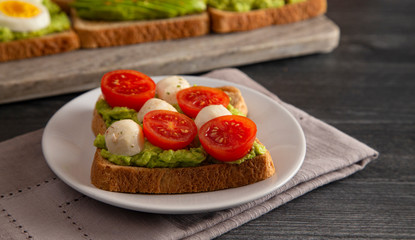 Tomato and Mozzarella Avocado Toast on a Wooden Table