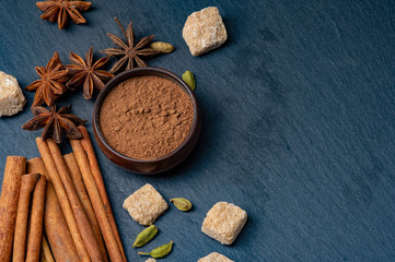 Brown star anise and cinnamon on a dark background. Ground cinnamon in a cup. Cardamom and cane...