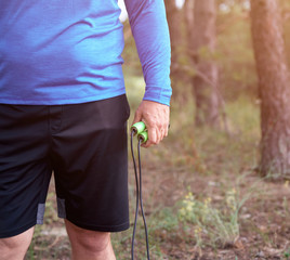 adult man in blue clothes holding a jump rope for playing sports