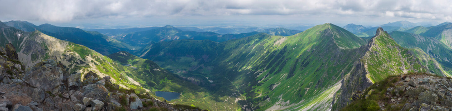 Panoramic view from Rohac peak on Western Tatra mountains or Rohace panorama. Sharp green mountains - ostry rohac, placlive and volovec with hiking trail on ridge. Summer blue sky white clouds.