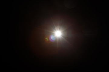 Lens Flare. Light over black background. Easy to add overlay or screen filter over photos. Abstract sun burst with digital lens flare background. Gleams rounded and hexagonal shapes, rainbow halo.