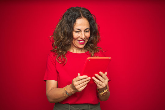 Middle Age Senior Woman Using Touchpad Tablet Over Red Isolated Background With A Happy Face Standing And Smiling With A Confident Smile Showing Teeth