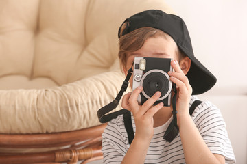 Cute little photographer with professional camera at home