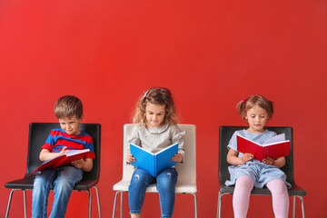 Fototapeta na wymiar Cute little children reading books on color background