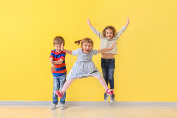 Cute little children having fun near color wall