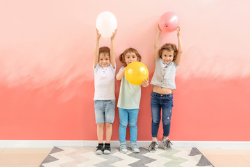 Cute little children with air balloons near color wall
