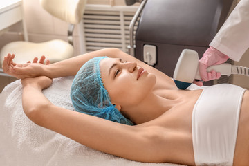 Beautiful woman undergoing procedure of laser hair removing in beauty salon