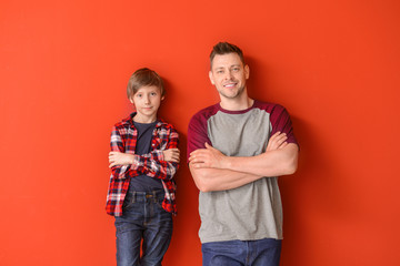 Portrait of father and son on color background