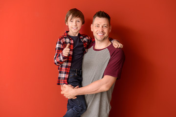 Portrait of father and son on color background