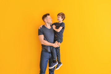 Portrait of father and son on color background