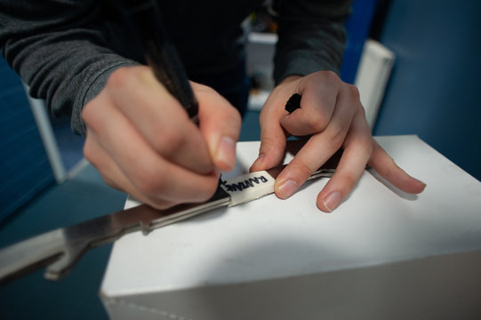 Ice hockey equipment: ice hockey equipment manager writing notes on ice skate blades