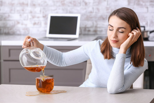 Sleepy Young Woman Spilling Tea On Kitchen Table