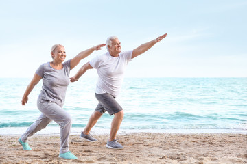 Mature couple practicing yoga at sea resort