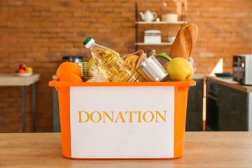 Box with donation food on table in kitchen
