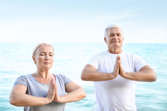 Mature Couple Practicing Yoga At Sea Resort